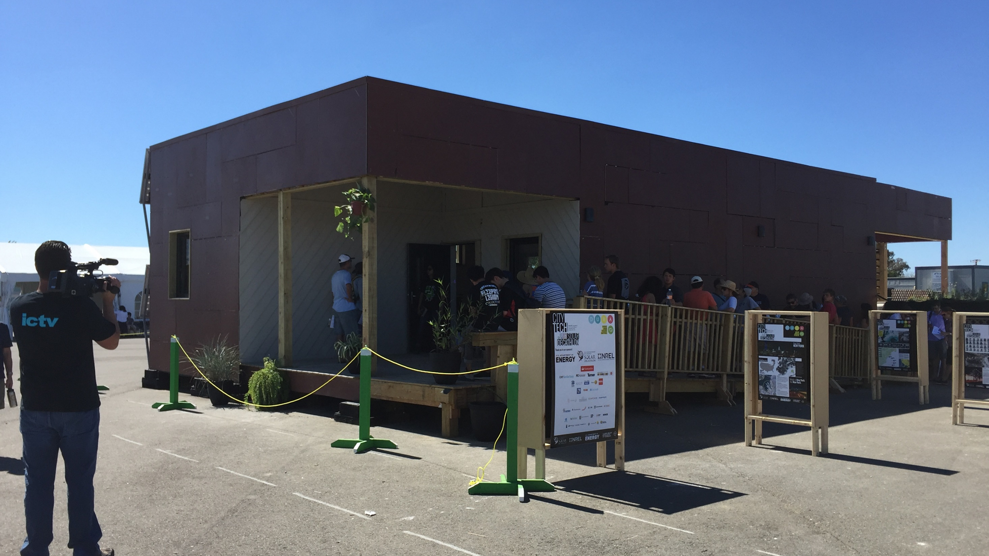 The completed DURA house on exhibition, with visitors, media coverage, and the CITY TECH sponsor board out front