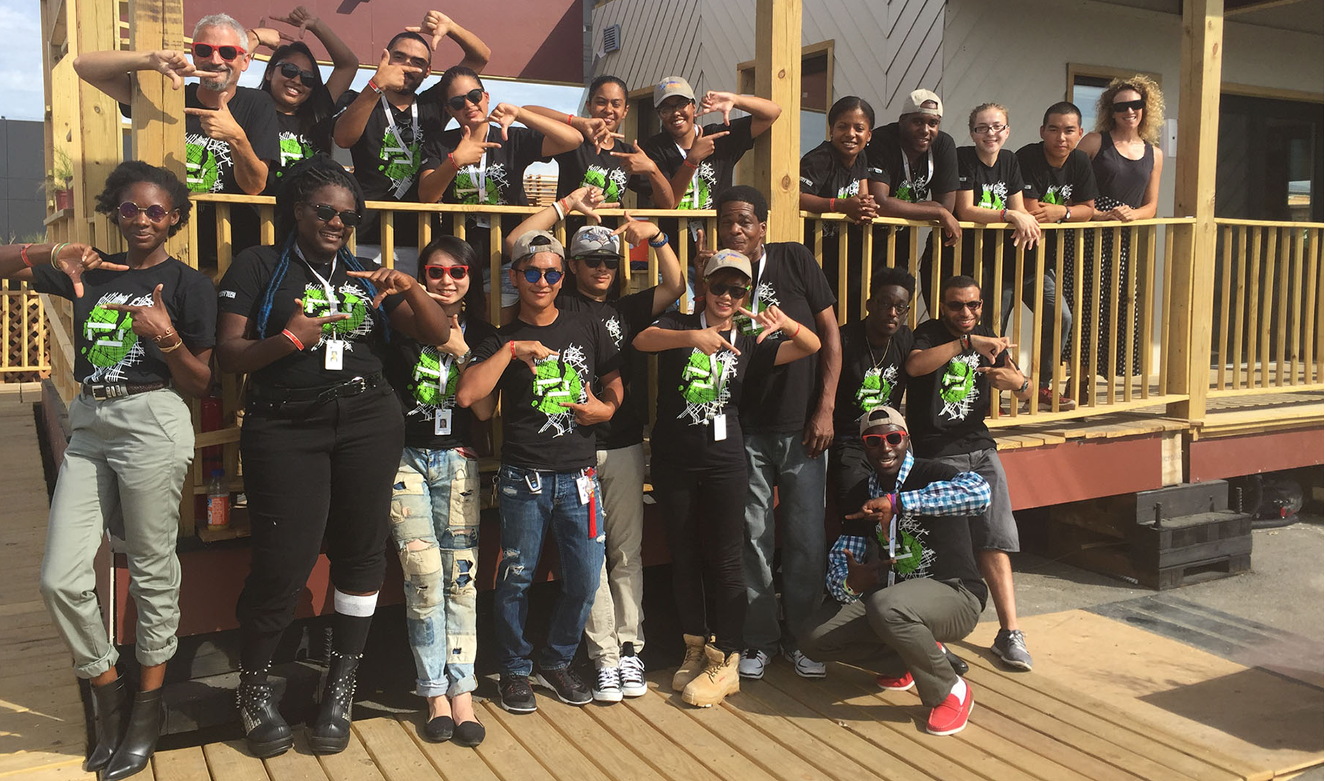 The full Team DURA group posing together on the house's porch and deck, wearing matching black team t-shirts